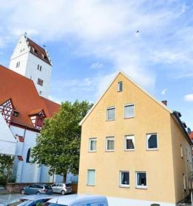 un edificio amarillo con una torre de reloj en el fondo en Ferienwohnung am Schloss Leipheim Nähe Legoland, en Leipheim