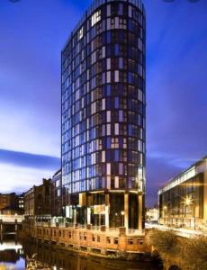 a tall building with blue windows next to a river at Spacious City Centre 2 bedroom apartment in Sheffield