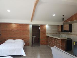 1 dormitorio con cama y pared de ladrillo en Chalet Villa Alejandra Del Pilar, en Quimbaya