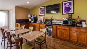 
a kitchen with a table, chairs, and a refrigerator at Best Western Catalina Inn in Tuscaloosa
