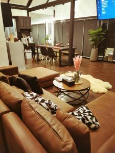 a living room with brown leather couches and a table at The Balcony pool villa in Ban Khanong Phra Nua