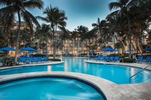 een zwembad met blauwe stoelen en palmbomen bij Wyndham Grand Rio Mar Rainforest Beach and Golf Resort in Rio Grande