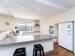 uma cozinha com armários brancos e um frigorífico branco em Woodland Heath Escape em Inverloch