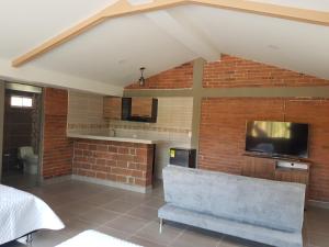 a living room with a tv and a brick wall at Chalet Villa Alejandra Del Pilar in Quimbaya