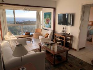 sala de estar con sofá blanco y TV en Piso alto con gran vista al mar y la isla, Torre Ibiza, en Punta del Este