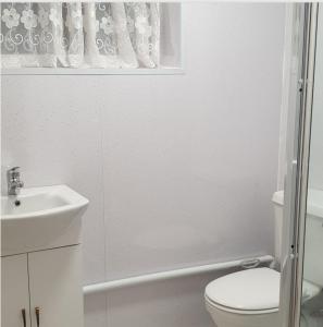 a white bathroom with a toilet and a sink at Lime House in Hayes