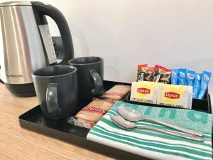 ein Tablett mit Kaffeetassen und anderen Artikeln auf der Theke in der Unterkunft The Osmond Motel & Apartments in Adelaide