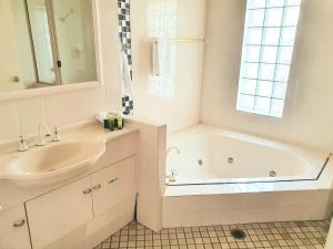 a white bathroom with a tub and a sink at McNevins Warwick Motel in Warwick