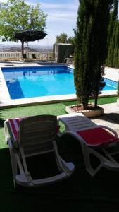 two lawn chairs and an umbrella next to a swimming pool at Vivienda Rural Villa Ruben in Jaén