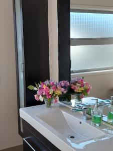 a bathroom sink with flowers in a mirror at The Grey Studio@13a in Carterton