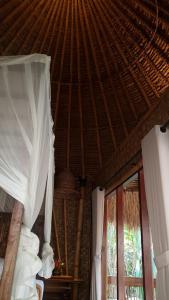 a bedroom with a straw roof and a bed with curtains at Geopark Village & Spa in Kintamani