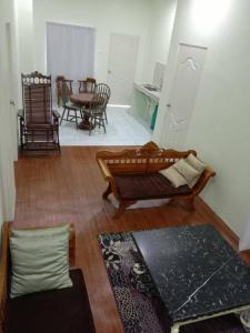 RaRa Homestay Hulu Langat في Kampong Jawa: غرفة معيشة مع أريكة وطاولة وكراسي