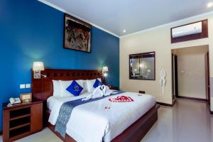een slaapkamer met een groot bed met blauwe muren bij Lumbung Sari Ubud Hotel - CHSE Certified in Ubud