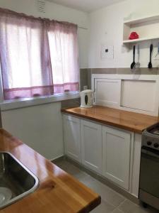 a kitchen with white cabinets and a wooden counter top at Cabaña en Traful, hermoso parque, parrilla e internet STARLINK in Villa Traful