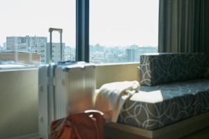 a hotel room with two suitcases and a window at FAV HOTEL KUMAMOTO in Kumamoto