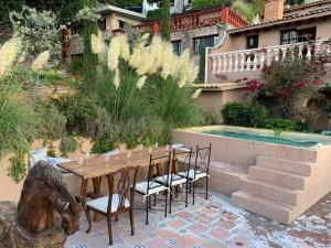 a wooden table and chairs next to a pool at Casa Vista 6BR Villa, 16p Jacuzzi Pool, Staff & Breakfast in San Miguel de Allende