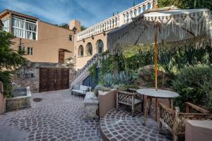 a patio with an umbrella and a table and benches at Casa Vista 6BR Villa, 16p Jacuzzi Pool, Staff & Breakfast in San Miguel de Allende +46 photos