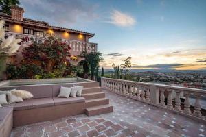 a couch on a balcony with a view of a city at Casa Vista 6BR Villa, 16p Jacuzzi Pool, Staff & Breakfast in San Miguel de Allende