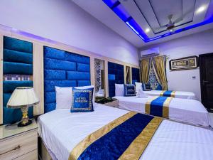 Duas camas num quarto com paredes azuis em Horizon Hotel em Lahore