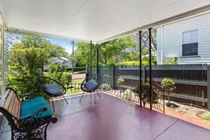 un porche grillagé avec trois chaises et une clôture dans l'établissement Artist's Cottage - Cosy Home in Quiet Leafy Street, à Toowoomba