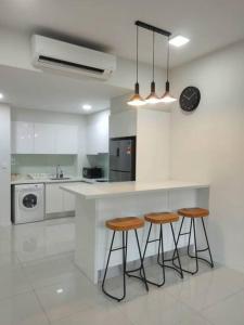 a kitchen with three stools and a counter with a clock at The Ridge @ KL East Mall & Condominium in Kuala Lumpur