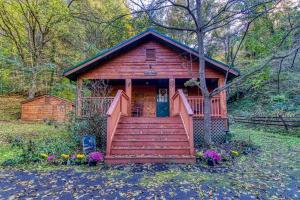 a small cabin with a staircase leading to the door at Cozy Creek - A Romantic Smoky Mountain Escape - Relax in a sheltered hot tub with creek-side & holler views - 3 mi to Gatlinburg, P Forge and National Park - listen to gentle mountain streams at this peaceful retreat in the heart of the Smokies in Pigeon Forge