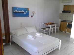 a bedroom with a white bed and a kitchen at Aeolos Hotel Apartments in Gythio