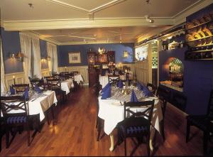 a restaurant with white tables and chairs and blue walls at Lillesand Hotel Norge in Lillesand