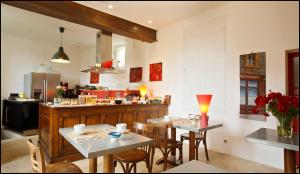 a kitchen with two tables and chairs and a counter at La Maison Rouge d'Uzes B&B in Uzès
