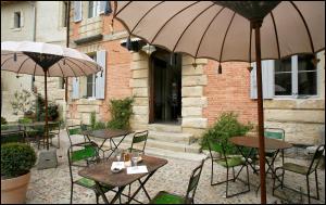 an outdoor patio with tables and chairs with umbrellas at La Maison Rouge d'Uzes B&B in Uzès