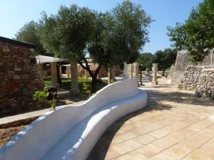 a bench in a park with trees and a building at Tenuta Serre in Salve