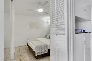 a white room with a bed and a closet at Cairns Esplanade Apartment in Cairns