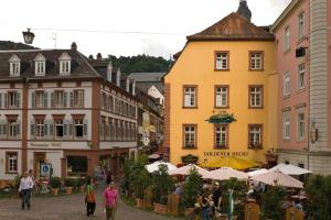 un grupo de personas caminando por una calle con edificios en Hotel Goldener Hecht en Heidelberg