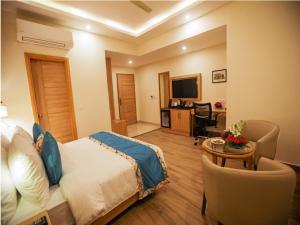 um quarto com uma cama, uma secretária e uma televisão em Elora Lords Eco Inn , Lucknow em Lucknow