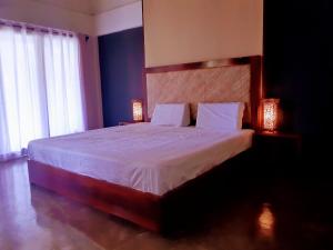 a bedroom with a large bed with two lamps at Lagkaw Siargao Villas in General Luna