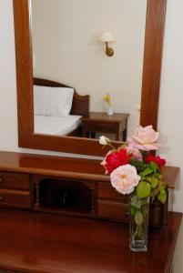 a vase of flowers on a table in front of a mirror at Aphrodite Hotel in Laganas