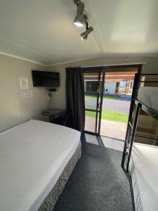 een slaapkamer met 2 bedden en een glazen schuifdeur bij Sapphire Springs Holiday Park and Thermal Pools in Katikati