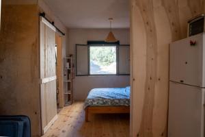 a bedroom with a bed and a window and a refrigerator at Cozy Galilee Getaway in Abirim