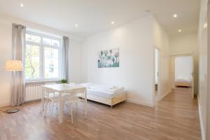a white room with a bed and a table and chairs at RAJ Living - 1 or 3 Room Apartments - 20 Min Messe DUS and Old Town DUS in Düsseldorf