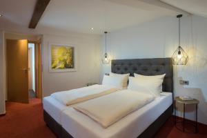 a large white bed with white sheets and pillows at Hotel Weinhof in Cochem