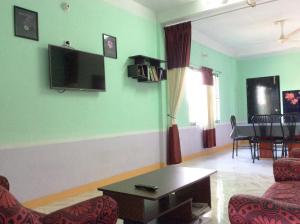 a living room with a couch and a tv on the wall at ApartmenT - Homestays in Sylhet