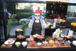 a person wearing a santa hat standing behind a table of desserts at Novotel Chennai Chamiers Road in Chennai