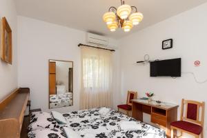 a bedroom with a bed and a desk and a television at Guest House Cesic in Dubrovnik