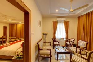 Schlafzimmer mit einem Bett, einem Tisch und Stühlen in der Unterkunft Hotel Floral Park in Kottayam