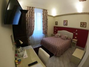 Una pequeña habitación con una cama y un televisor. en Five Roses Bed & Breakfast, en Pisa