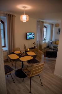 uma sala de estar com duas mesas e cadeiras e uma televisão em Calme et cosy em Obernai