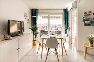 a kitchen with a table and chairs and a television at Port-Fréjus, LE PALADIEN, appartement 2 pièces climatisé, terrasse & parking in Fréjus