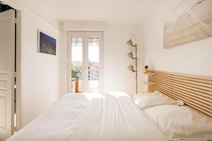 a white bedroom with a large bed and a window at Port-Fréjus, LE PALADIEN, appartement 2 pièces climatisé, terrasse & parking in Fréjus