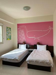 two beds in a room with a pink wall at J house 拉法民宿 in Taitung City