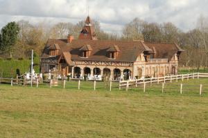 una casa grande en un campo con una valla en Le Manoir de Goliath, en Toutainville